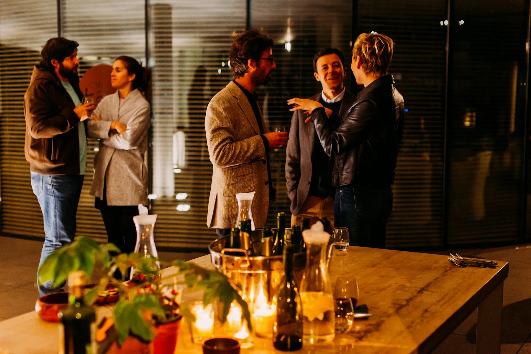 Friends talking around a candlelit table with drinks in the evening